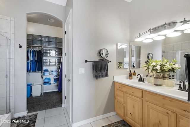 bathroom with tile patterned floors, a shower with door, and vanity