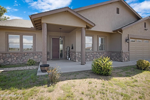 doorway to property with a yard, a porch, and a garage