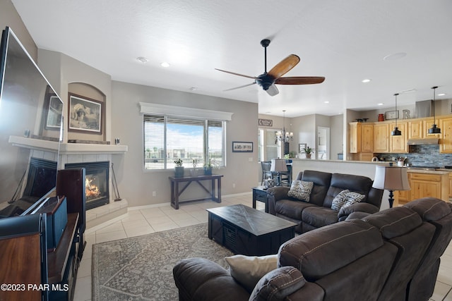 tiled living room featuring ceiling fan with notable chandelier and a tile fireplace