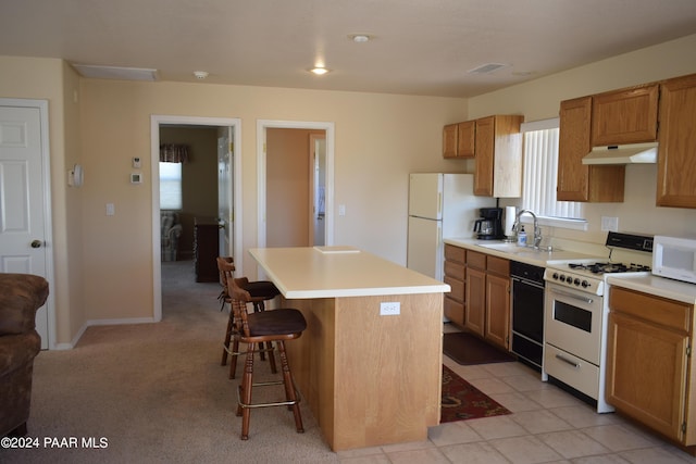 kitchen featuring white appliances, light colored carpet, sink, a kitchen island, and a breakfast bar area