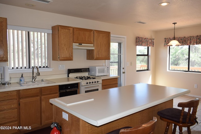 kitchen featuring sink, hanging light fixtures, tile patterned flooring, white appliances, and a breakfast bar area