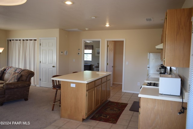 kitchen featuring a breakfast bar, a kitchen island, light tile patterned floors, and sink