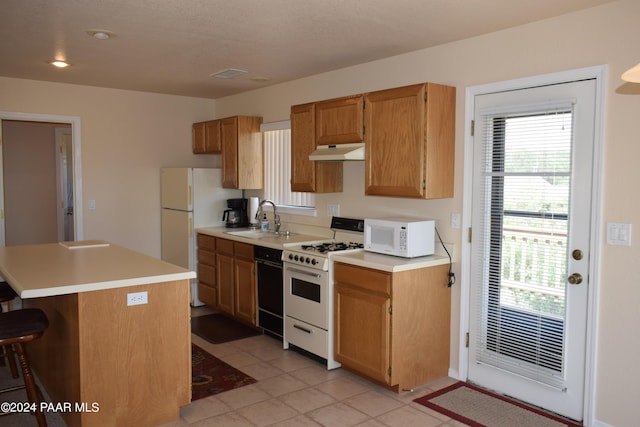 kitchen featuring plenty of natural light, sink, light tile patterned floors, and white appliances