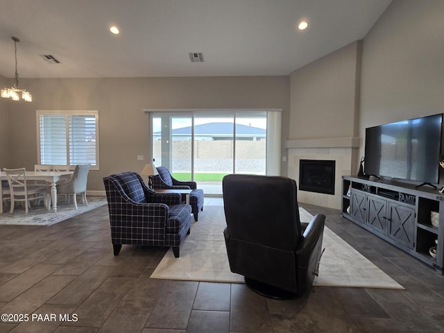 living room featuring a tiled fireplace and an inviting chandelier