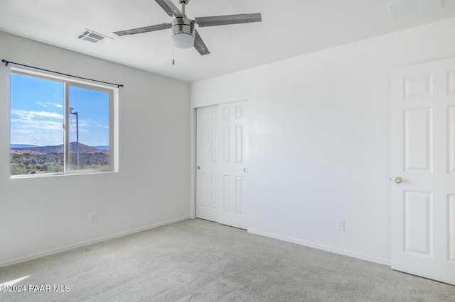 spare room with ceiling fan and light colored carpet