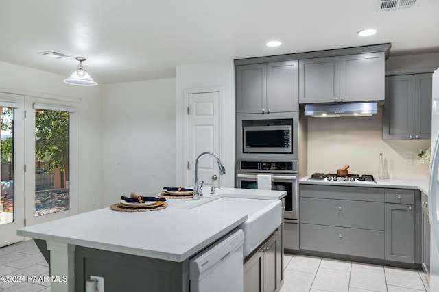 kitchen with stainless steel appliances, gray cabinets, and a center island with sink