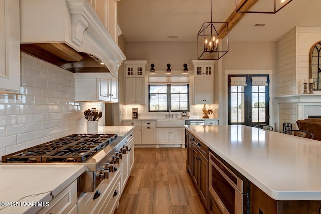 kitchen with visible vents, light wood-type flooring, custom range hood, white cabinets, and stainless steel appliances