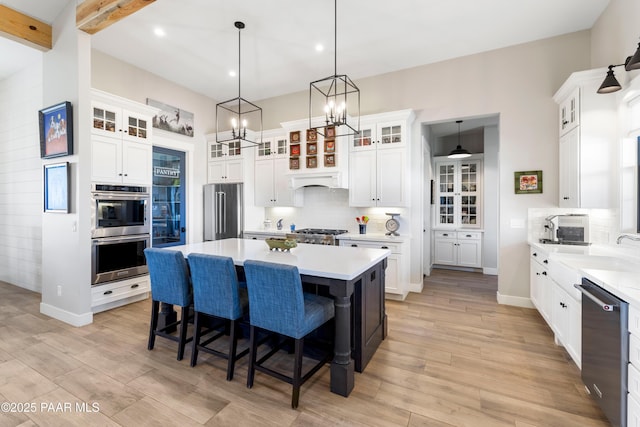 kitchen featuring a sink, a kitchen breakfast bar, stainless steel appliances, light wood finished floors, and decorative backsplash