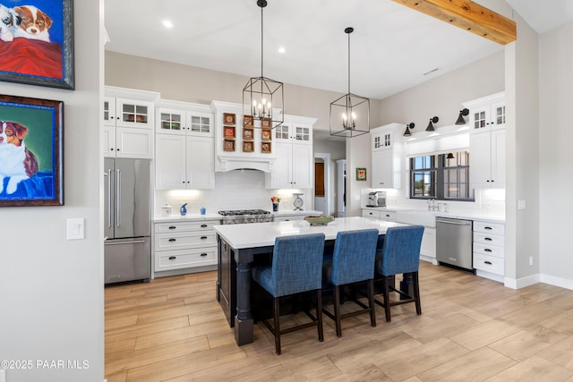 kitchen with backsplash, a kitchen island, a breakfast bar, light countertops, and stainless steel appliances