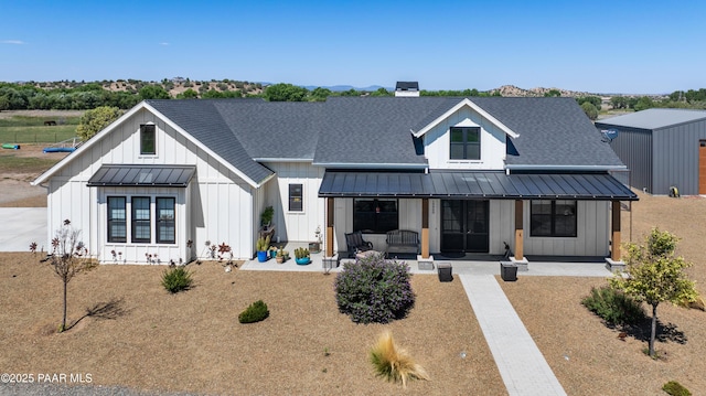 back of property featuring board and batten siding, a porch, roof with shingles, metal roof, and a standing seam roof