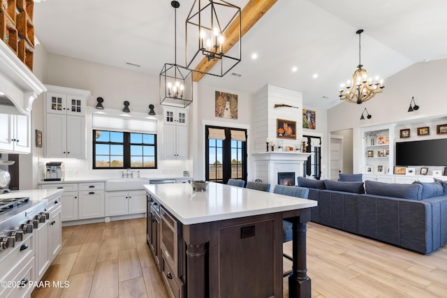 kitchen featuring a sink, light wood-style flooring, a warm lit fireplace, and a chandelier