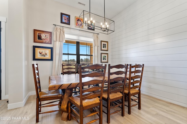 dining space with visible vents, baseboards, a chandelier, and light wood finished floors