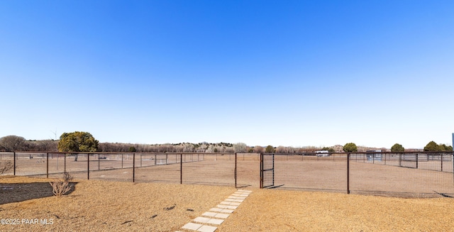 view of yard with an enclosed area, a rural view, and fence