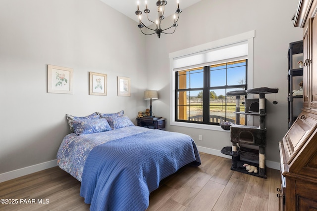 bedroom featuring baseboards, an inviting chandelier, and wood finished floors