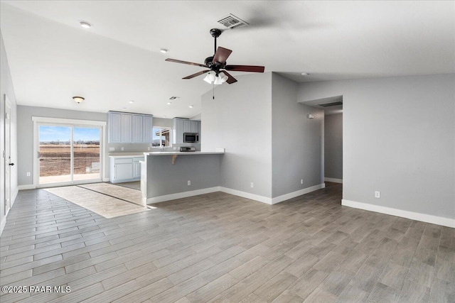 unfurnished living room with light hardwood / wood-style floors, ceiling fan, and vaulted ceiling