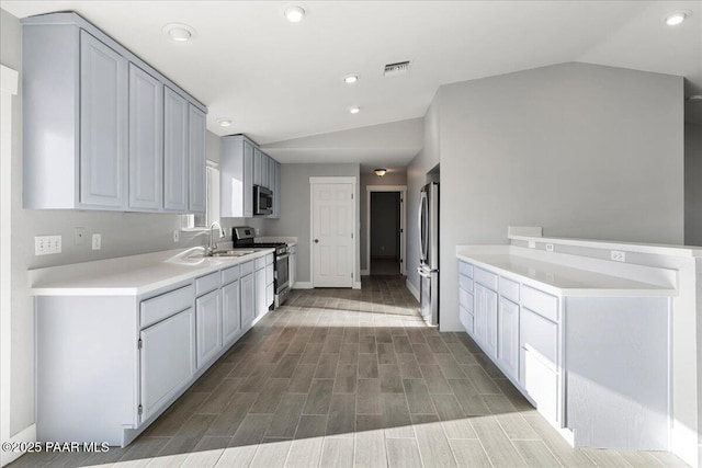 kitchen featuring lofted ceiling, appliances with stainless steel finishes, gray cabinetry, and sink