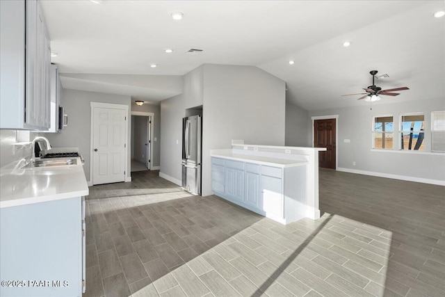 kitchen with vaulted ceiling, stainless steel refrigerator, ceiling fan, sink, and white cabinetry