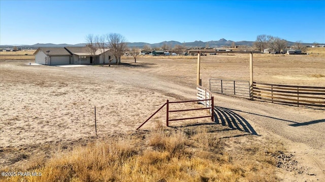 view of yard featuring a garage, a rural view, and a mountain view