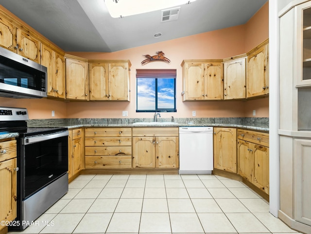 kitchen featuring light tile patterned flooring, stainless steel appliances, lofted ceiling, and sink