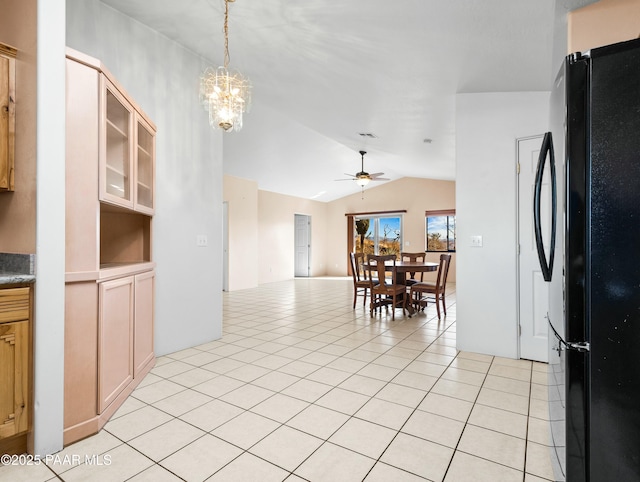 kitchen with ceiling fan with notable chandelier, light tile patterned floors, black fridge, and lofted ceiling