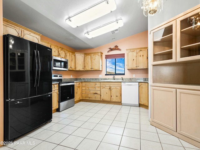 kitchen featuring appliances with stainless steel finishes, light tile patterned flooring, light brown cabinetry, lofted ceiling, and sink