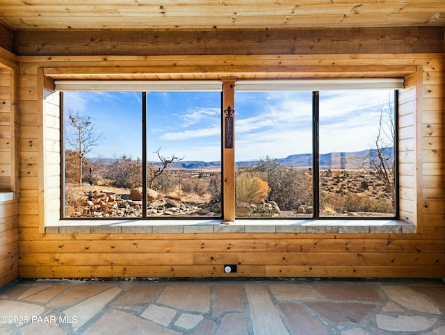 interior space with a healthy amount of sunlight, a mountain view, and wooden walls