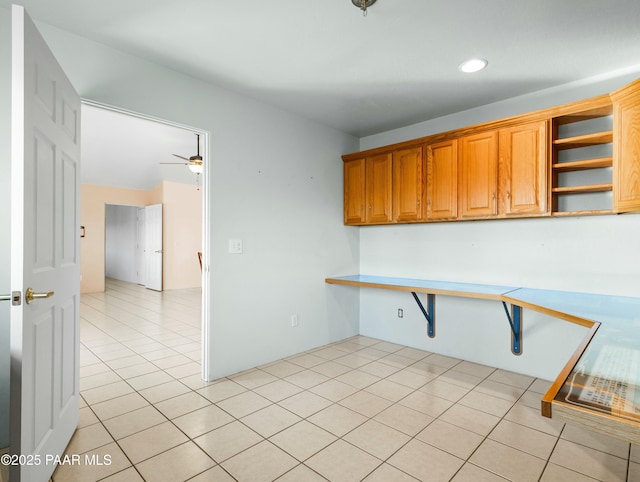 kitchen featuring ceiling fan, light tile patterned floors, and built in desk