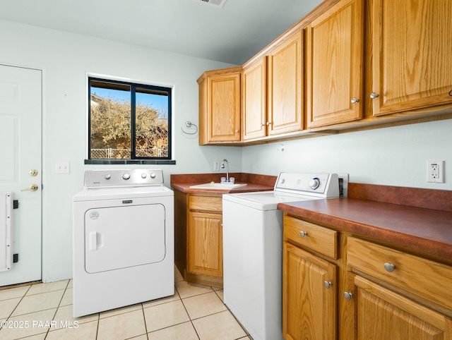 washroom with cabinets, light tile patterned floors, washer and dryer, and sink