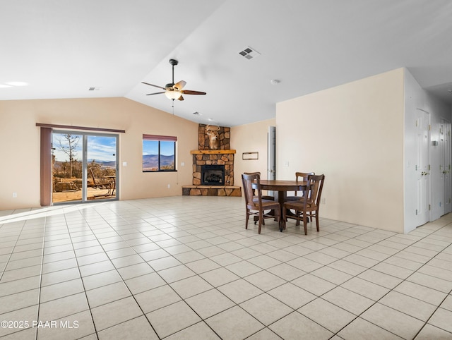 tiled dining area with ceiling fan, lofted ceiling, and a fireplace