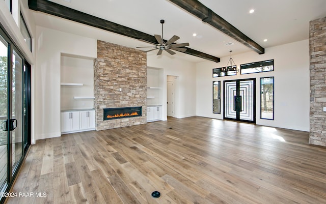 unfurnished living room with a fireplace, ceiling fan, light hardwood / wood-style flooring, and beamed ceiling