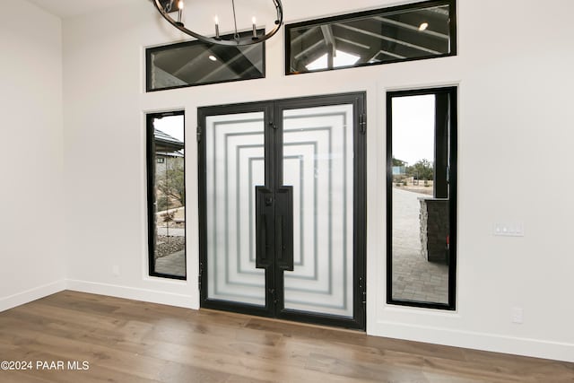 foyer entrance featuring hardwood / wood-style flooring, a wealth of natural light, lofted ceiling, and a notable chandelier