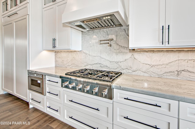 kitchen with tasteful backsplash, white cabinetry, dark wood-type flooring, and custom exhaust hood