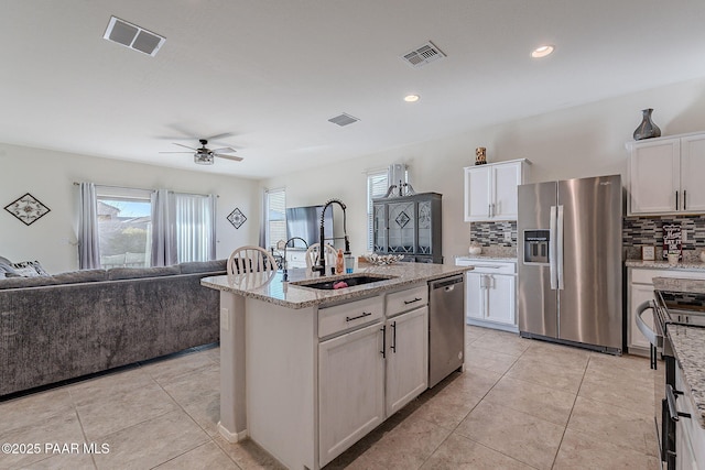 kitchen with decorative backsplash, sink, white cabinetry, an island with sink, and stainless steel appliances