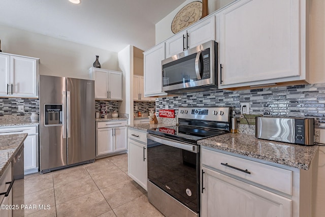 kitchen with light tile patterned flooring, stainless steel appliances, white cabinetry, and tasteful backsplash