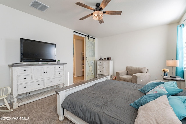 bedroom with ceiling fan, a barn door, and carpet floors