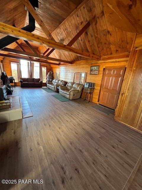 unfurnished living room featuring beam ceiling, high vaulted ceiling, wood finished floors, wooden walls, and wooden ceiling