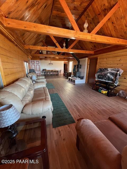 living area featuring lofted ceiling with beams, wood ceiling, wood finished floors, and wood walls