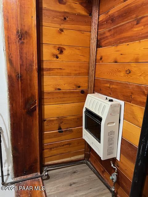 interior details featuring wood finished floors, heating unit, and wood walls