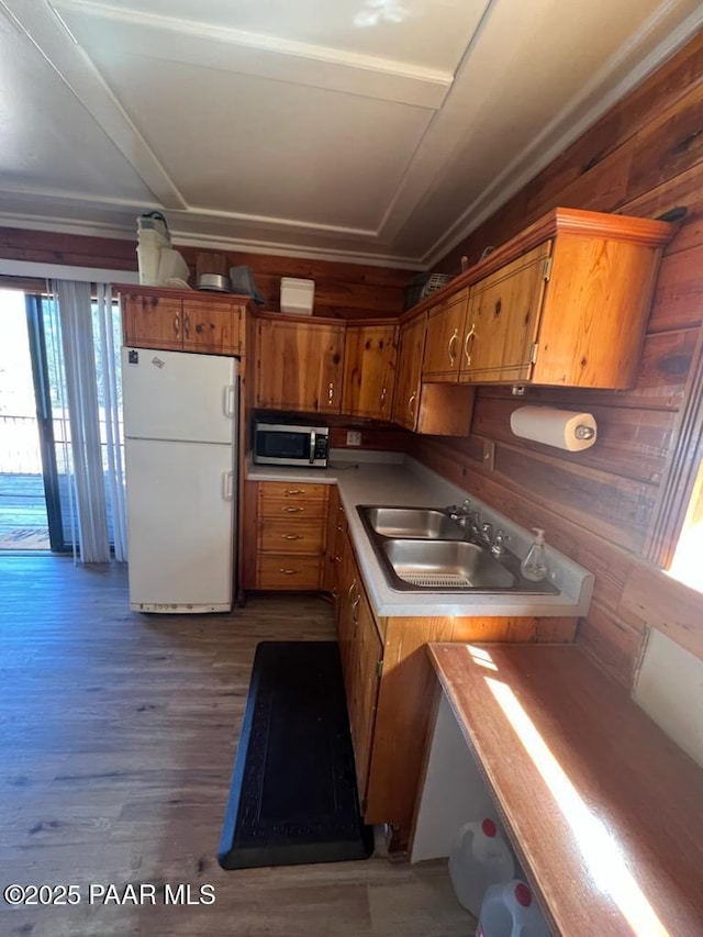 kitchen featuring dark wood-style flooring, freestanding refrigerator, a sink, stainless steel microwave, and brown cabinets