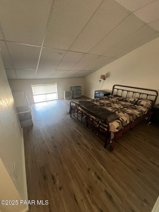 bedroom with a drop ceiling and wood finished floors