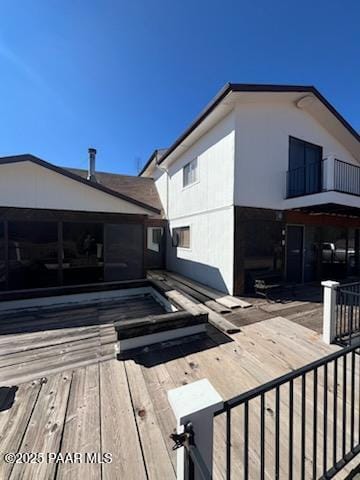 view of side of home featuring a wooden deck and a balcony