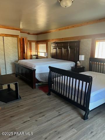 bedroom with crown molding and wood finished floors