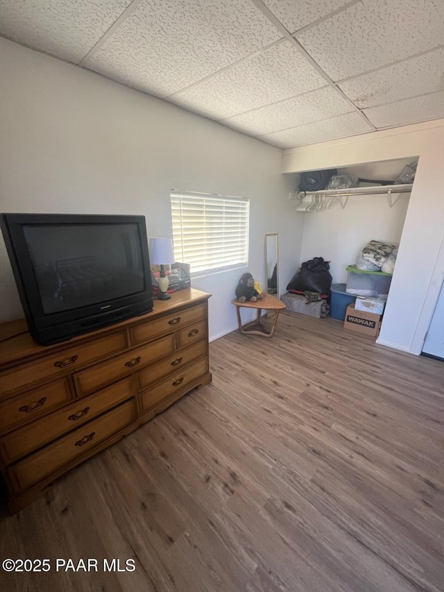 bedroom featuring a drop ceiling, a closet, and wood finished floors