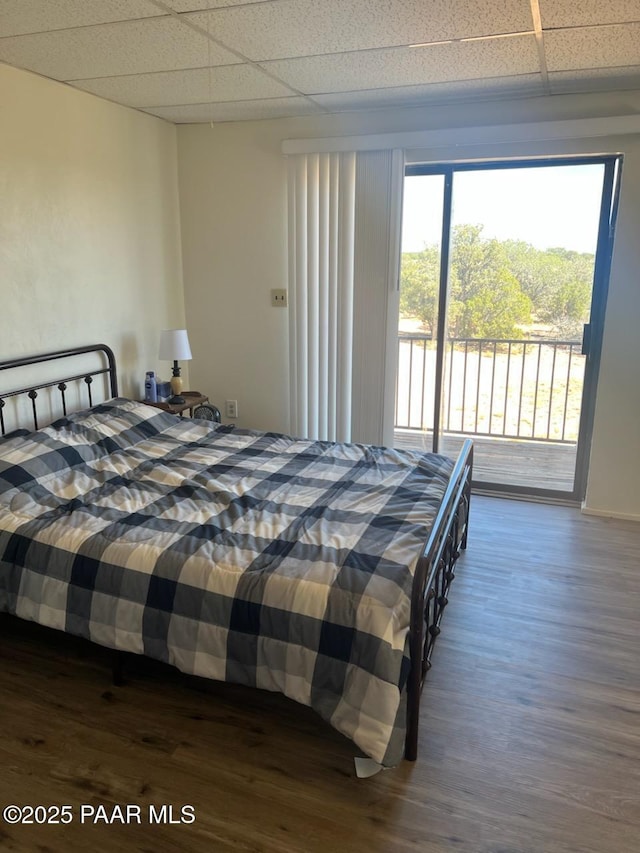 bedroom with access to exterior, a drop ceiling, and dark wood-style floors