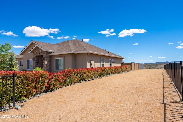 10181 E Old Black Canyon Hwy, Dewey-Humboldt, AZ 86327 - view of side of home featuring stucco siding, fence, stone siding, and a shingled roof