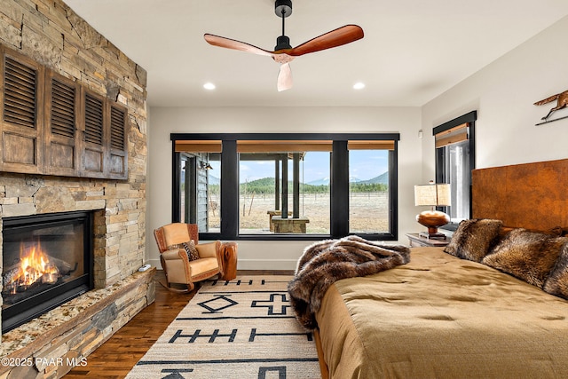 8222 N Spring Valley Rd, Parks, AZ 86018 - bedroom with dark wood-type flooring, ceiling fan, recessed lighting, and a stone fireplace