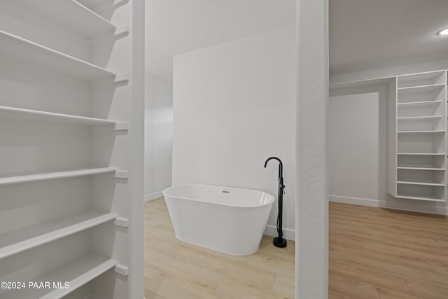 bathroom with hardwood / wood-style flooring and a bath