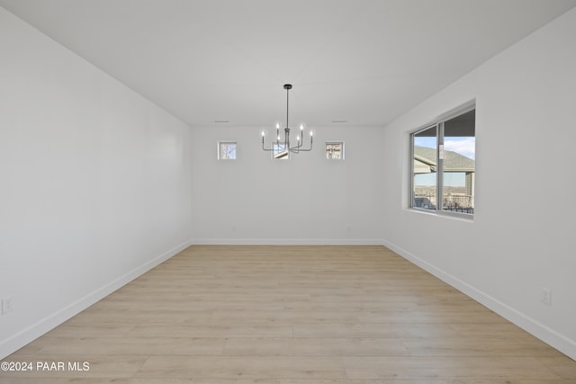 unfurnished dining area featuring an inviting chandelier and light hardwood / wood-style flooring