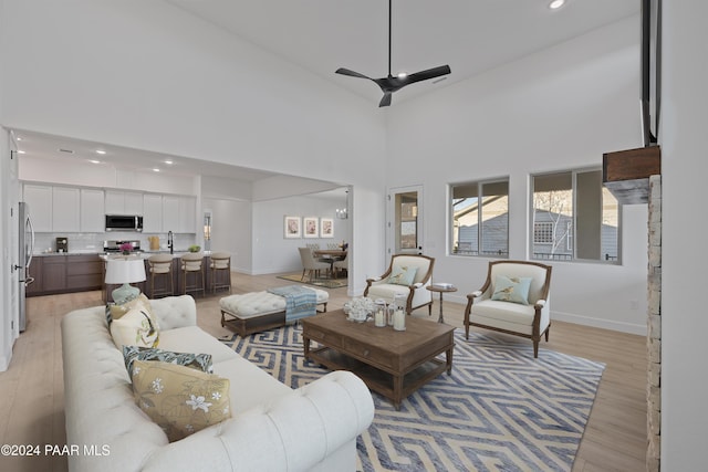 living room with light hardwood / wood-style flooring, high vaulted ceiling, ceiling fan, and sink