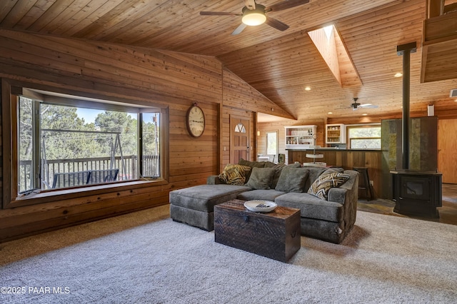 1135 N Rose Quartz Dr, Prescott, AZ 86303 - carpeted living room featuring ceiling fan, wood ceiling, a wood stove, vaulted ceiling, and wooden walls